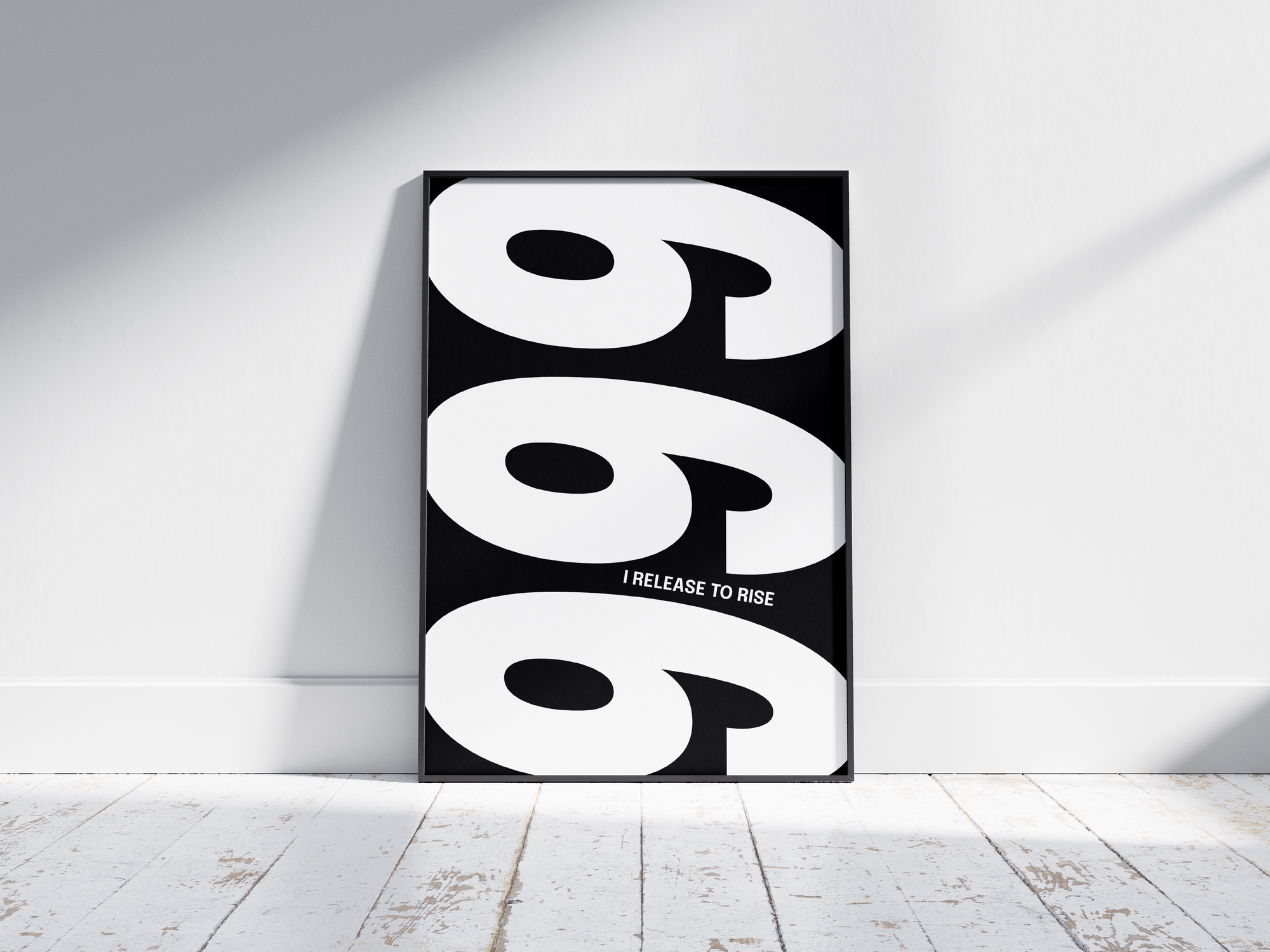 Minimalist black and white abstract poster featuring the repeated number 999 design and the quote "I release to rise," framed and leaning against a white wall. Inspiring modern wall art for a transformative, contemporary home or office interior.