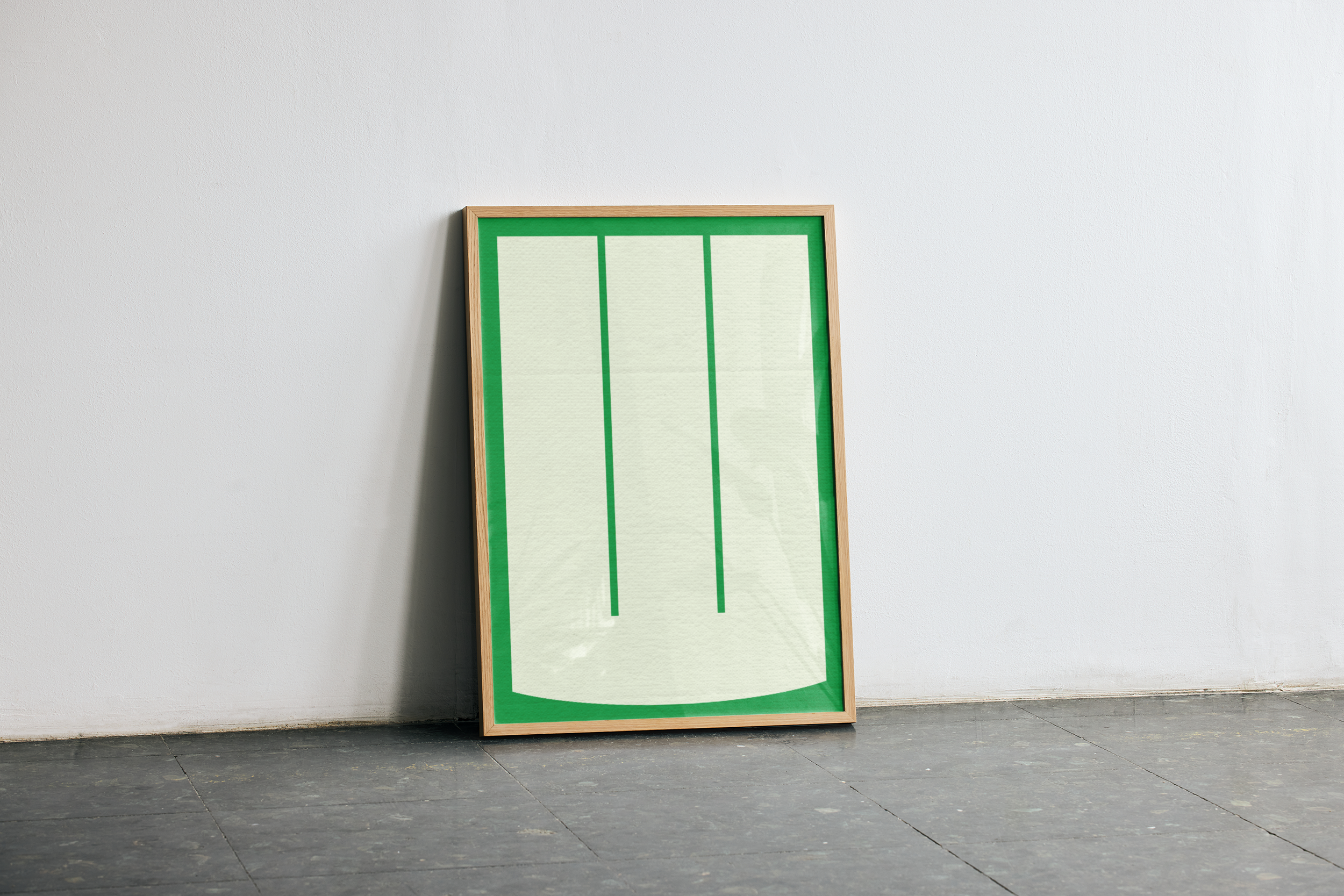 A light wooden framed poster with a minimalist design of three vertical green lines on a cream background, surrounded by a bright green border. It leans against a white wall on a dark grey floor.