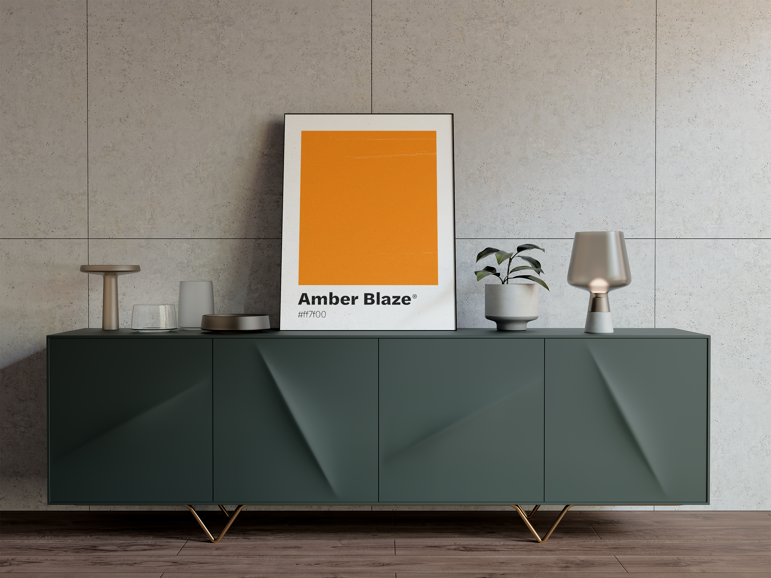 A framed print featuring a large block of bright orange labeled "Amber Blaze," sitting on a modern dark green sideboard with a plant and a lamp against a tiled concrete wall.