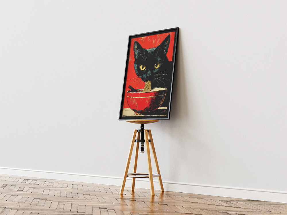 A unique and bold Pop Art style print featuring a black cat with piercing yellow eyes eating ramen noodles from a red bowl, set against a vibrant red background. Perfect for a kitchen, dining room, or a fun, quirky space. The framed print is displayed vertically on a wooden tripod stand against a minimalist white wall, creating an artistic and unconventional display.