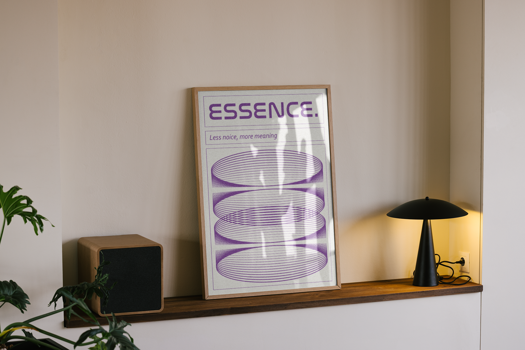 A framed modern abstract poster with the word "ESSENCE." and a slogan, featuring four horizontal stacks of concentric purple lines, propped on a wooden shelf next to a wooden speaker and a black, saucer-shaped table lamp.