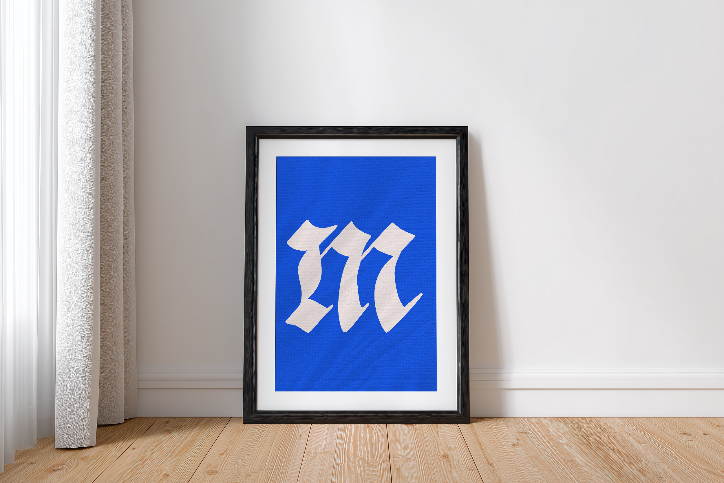 A black-framed poster featuring a white, gothic-style triple 'm' on a vibrant blue background, leaning against a white wall with light wooden flooring. A white curtain is visible on the left.