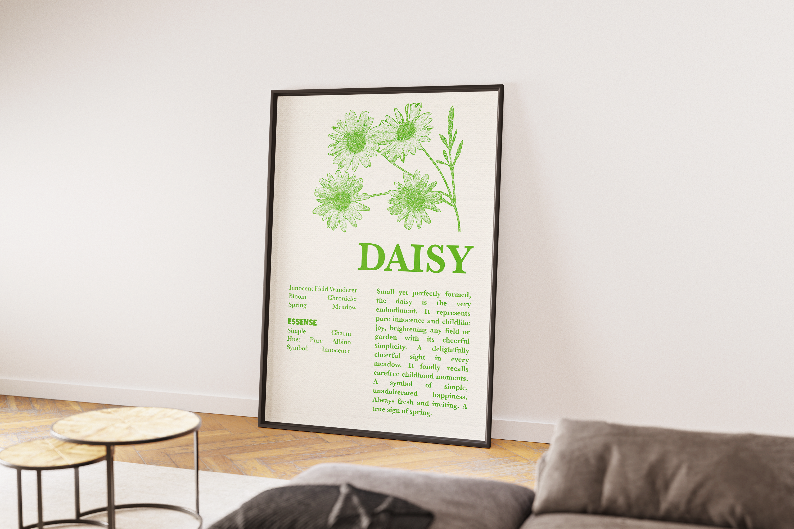 A black-framed poster featuring a detailed green sketch and description of a Daisy flower, leaning on a wooden floor next to a cozy gray sofa and two small round side tables.