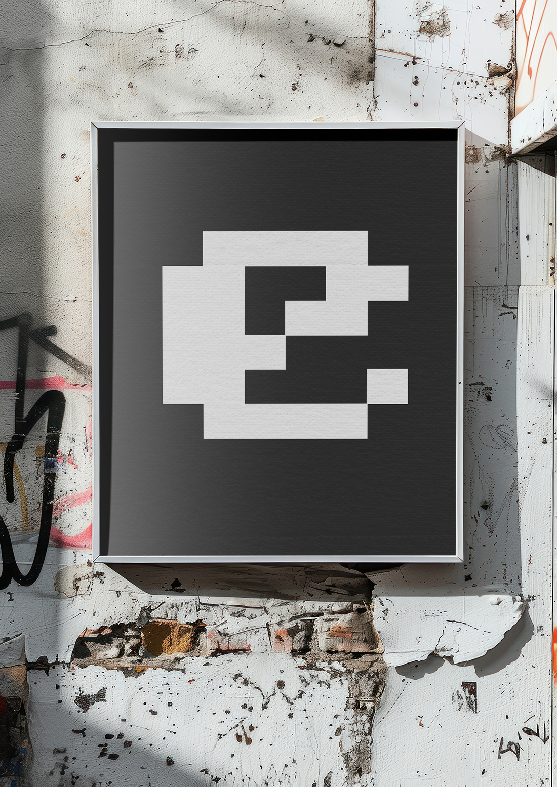 A square-framed print featuring a white, pixelated/abstract version of the letter 'E' on a black background, mounted on a rough, graffiti-covered outdoor wall.